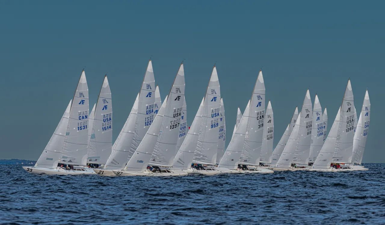 A group of sailboats with white sails competing in a race on the open water.